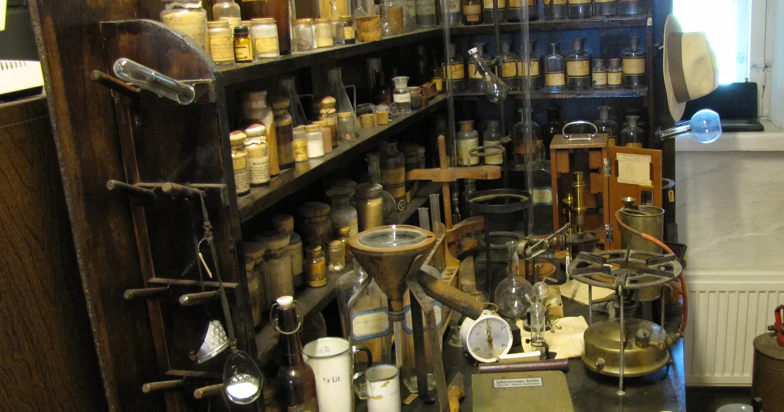 Antique laboratory shelves of glass bottles, funnels and a balance in a museum