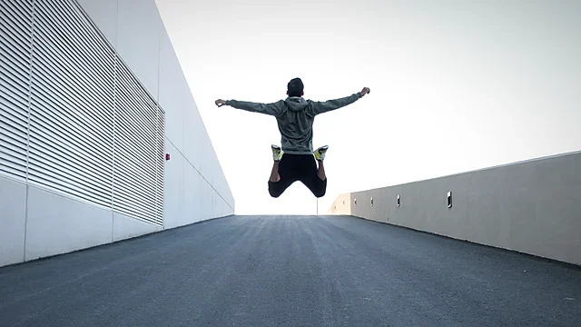 Athlete jumping high between white walls under a bright sky