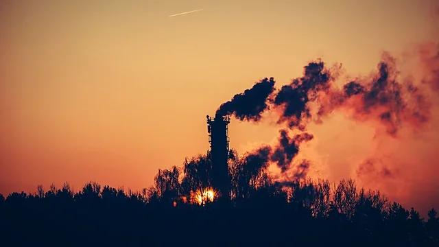 Industrial chimneys silhouetted against an orange dawn sky