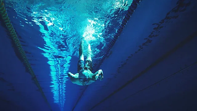 Swimmer diving underwater in a bright turquoise pool