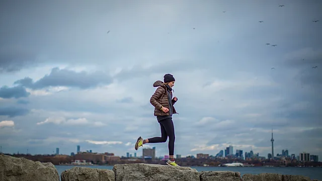 Runner on a waterfront path with a city skyline behind