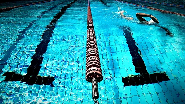 Swimmer racing down a lane in a vivid blue pool