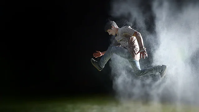 Athlete leaping through dramatic smoke at night