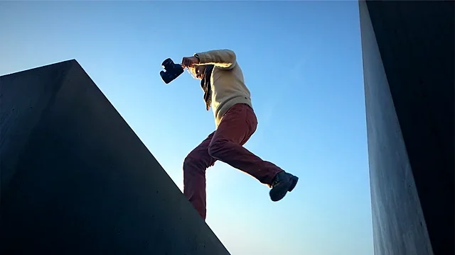 Free runner leaping between concrete walls under a blue sky