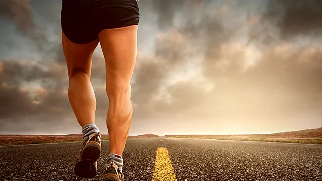 Runner striding down an open road under a dramatic sky