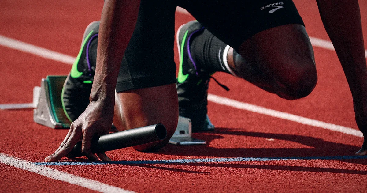 Sprinter crouched in the starting blocks on a red running track