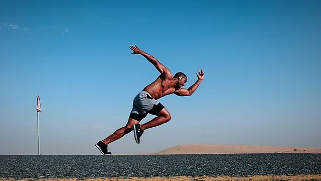 Sprinter in full flight against a deep blue sky