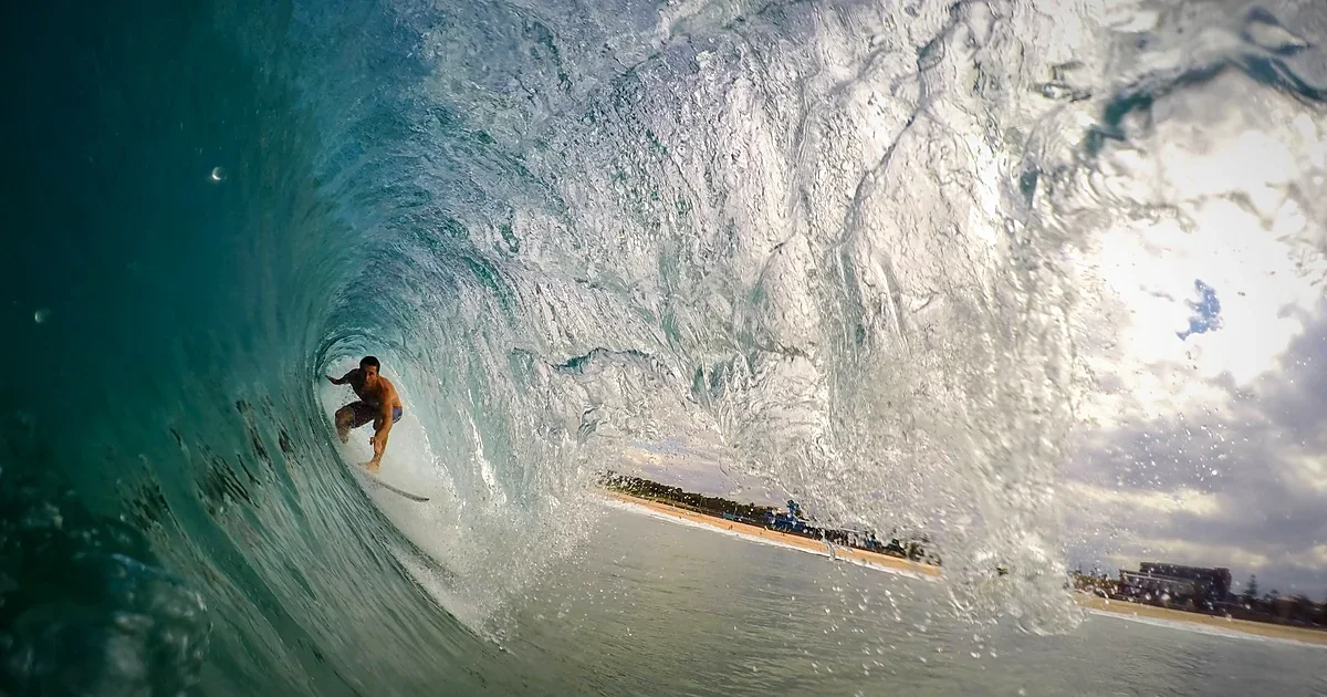 Surfer riding deep inside a curling turquoise wave