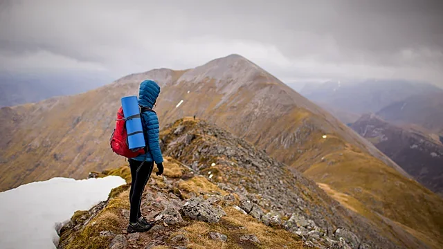 Mountaineer on a snowy ridge under a cloudy sky