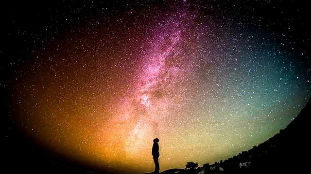 Starry night sky over a dark landscape