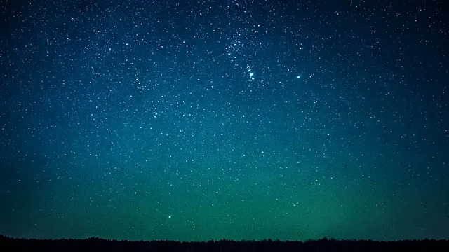 Star-filled night sky over a dark landscape