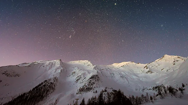 Snowy mountain peaks under a starry night sky