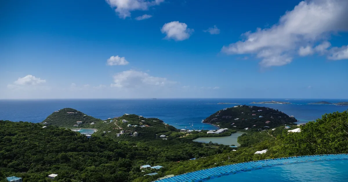 Curved infinity pool overlooking a tropical bay and green hills