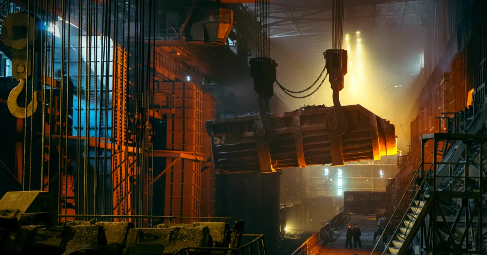 Steel hall glowing orange as molten metal is poured under industrial lights