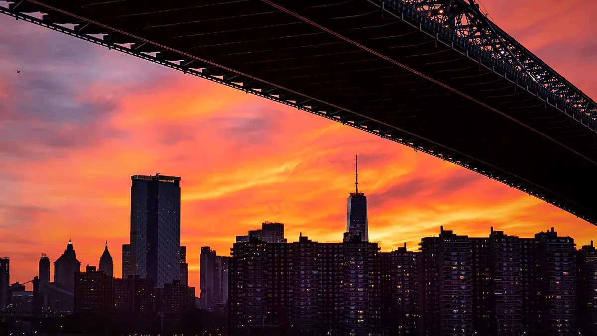 City skyline and bridge glowing under a pink and orange sunset sky