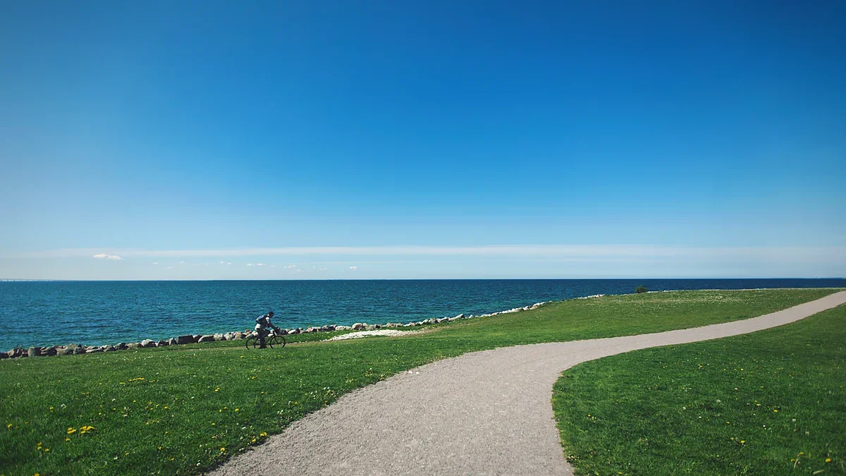 Cyclist riding a gravel trail beside coastal grass