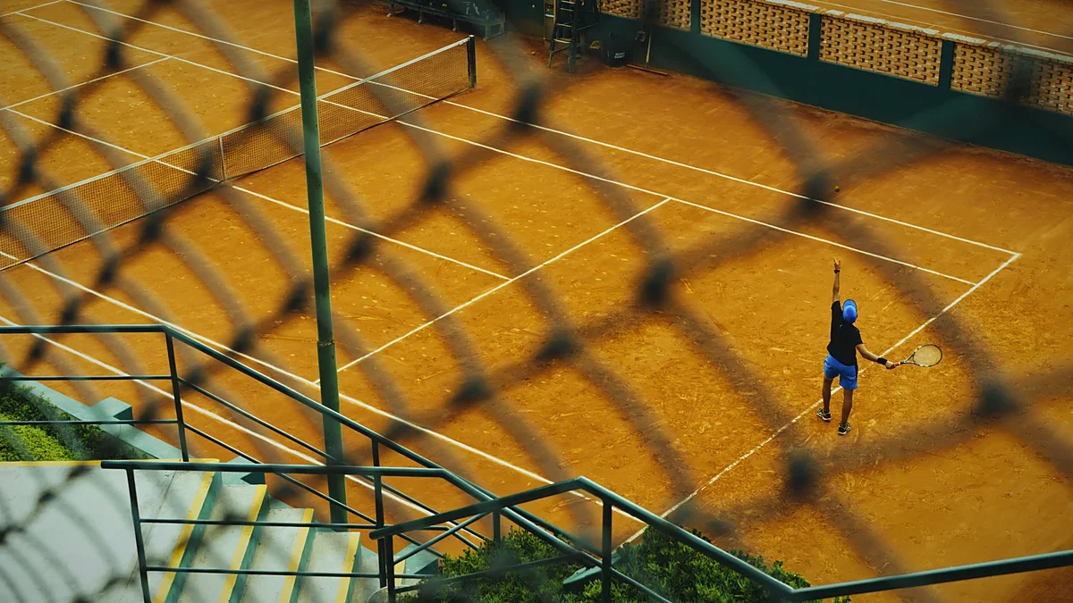 Tennis player in action on a sunlit grass lawn