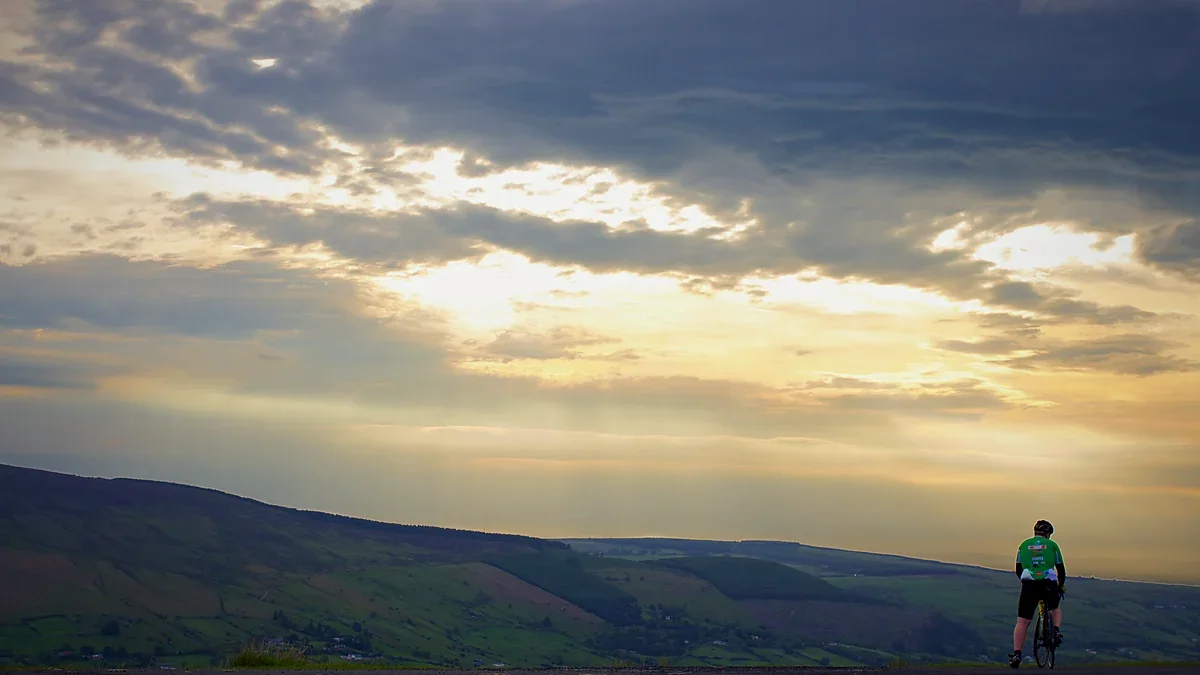 Cyclist riding through rolling hills at sunset