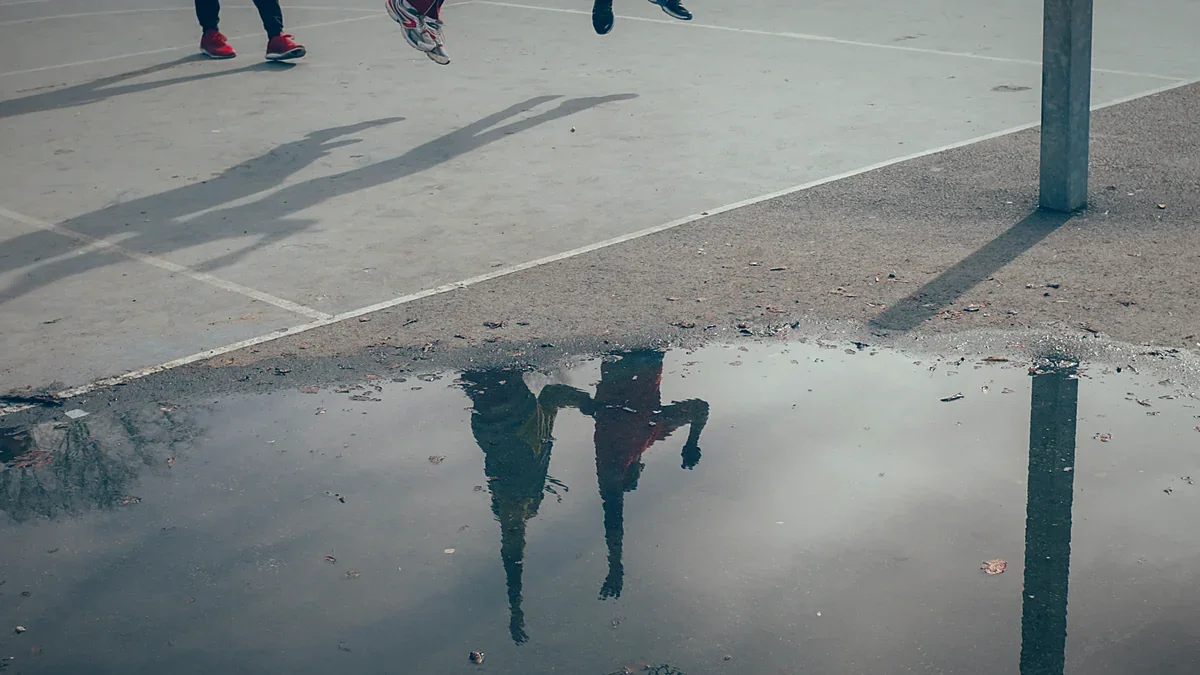 Athletes leaping for a basketball on wet asphalt