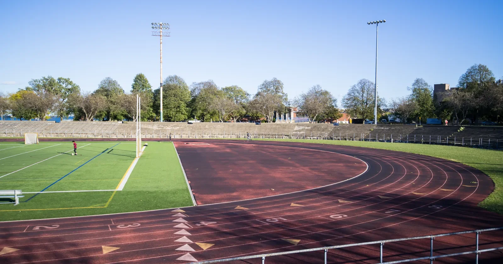 Empty outdoor running track and stadium under a clear blue sky
