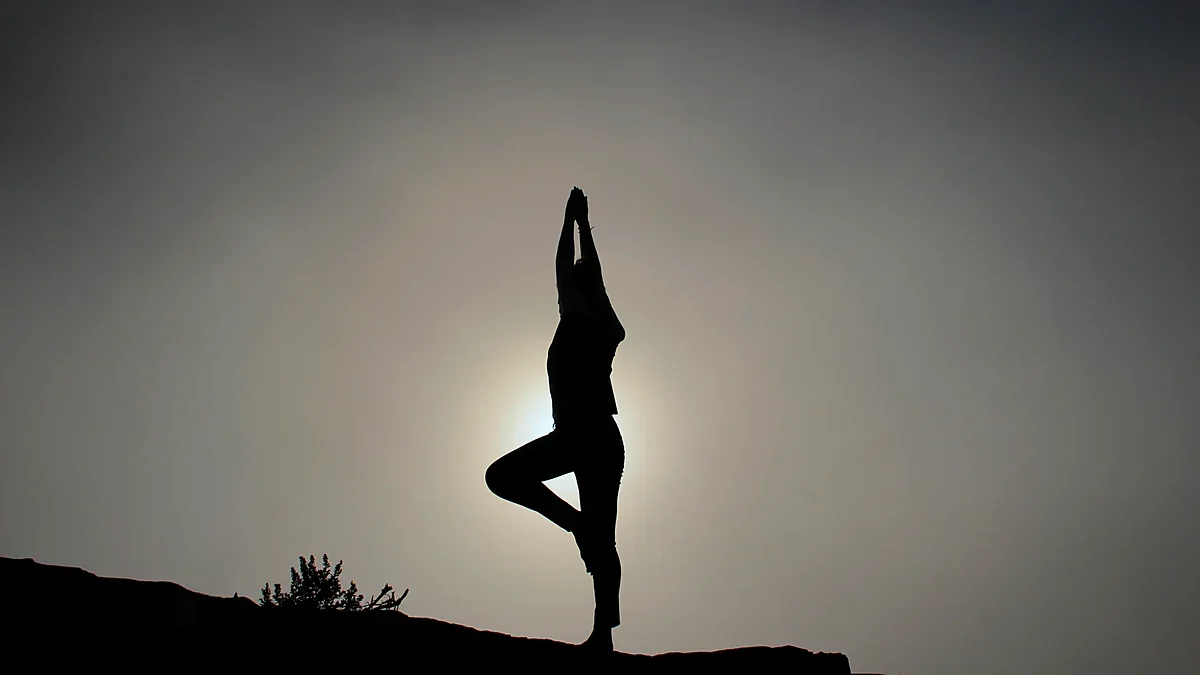 Yoga balance pose silhouetted against a hazy sun