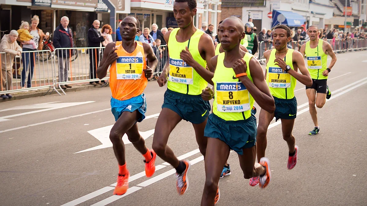Runners racing down a city street lined with spectators