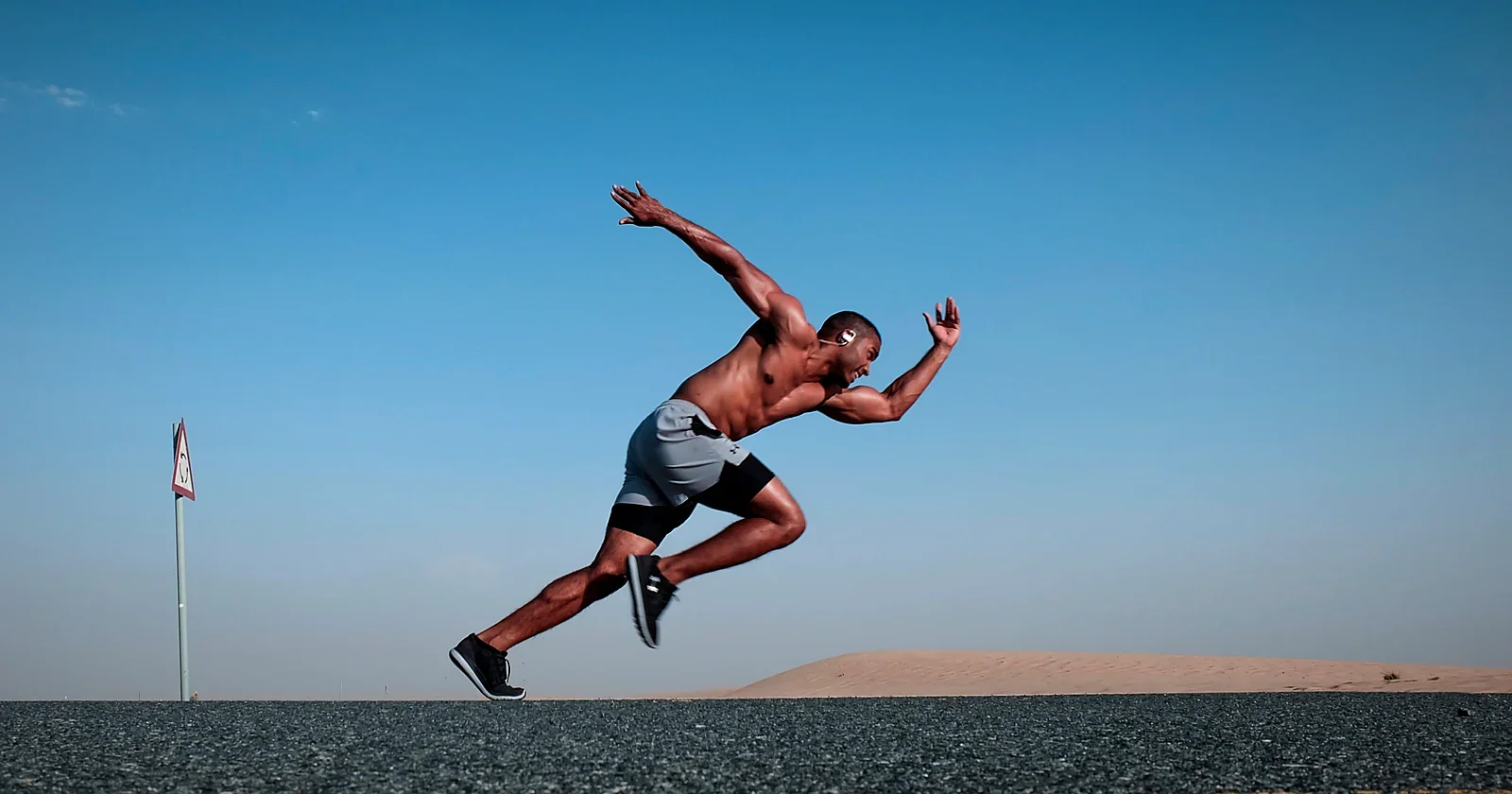 Sprinter in full flight against a deep blue sky
