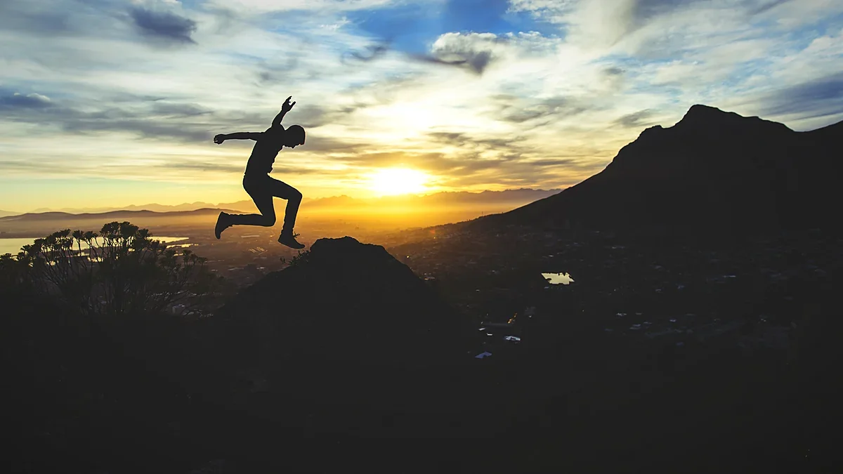 Silhouette of a runner leaping on a ridge at sunset