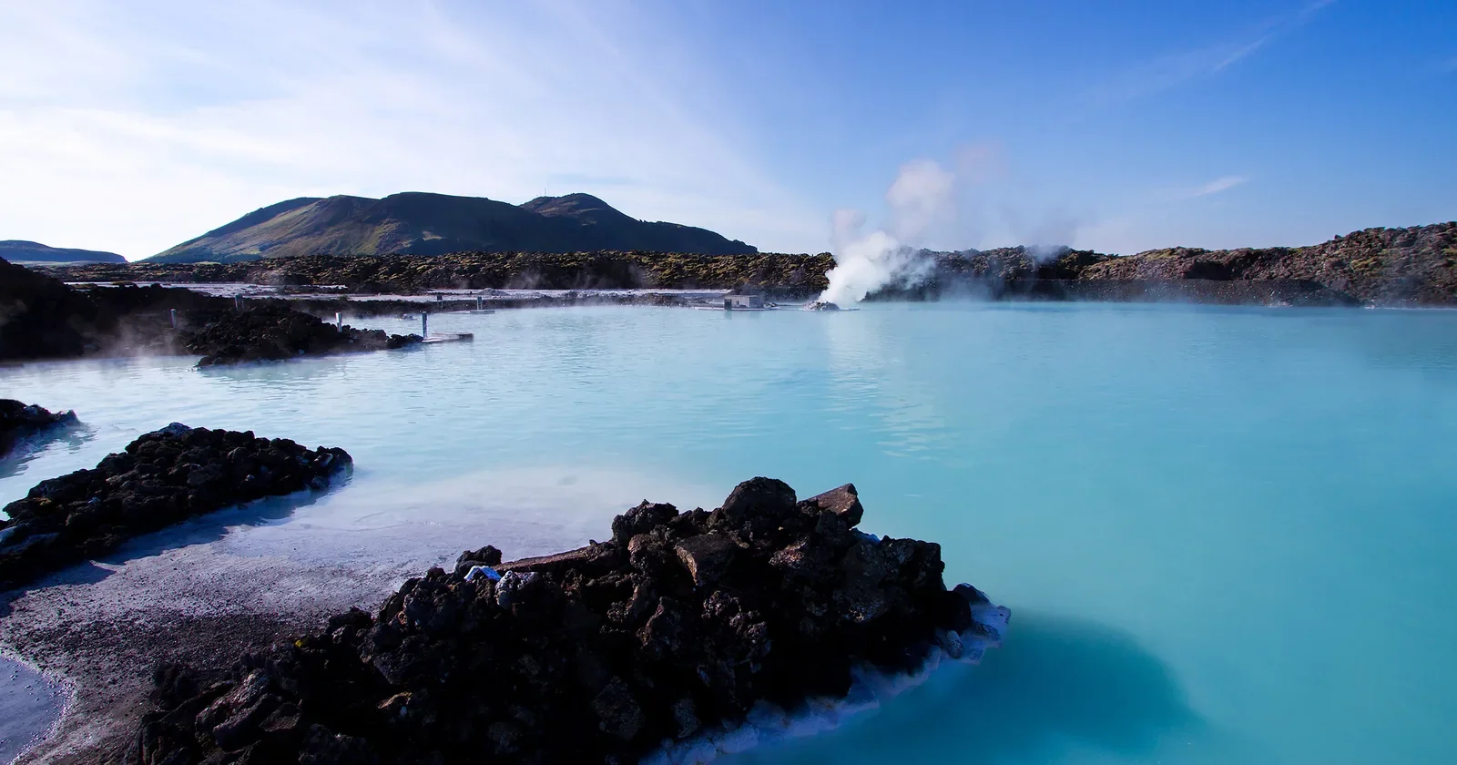 Milky blue geothermal lagoon with dark lava rocks in Iceland