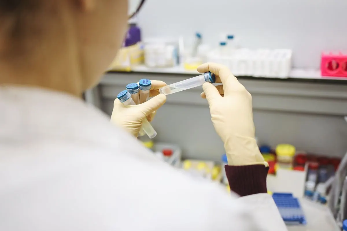 Gloved laboratory hands inspecting sample tubes during receiving identity checks